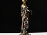 a bronze statue of a woman holding a book on a marble base