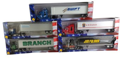 Trois camions miniatures sont présentés dans une vitrine avec un drapeau en arrière-plan.