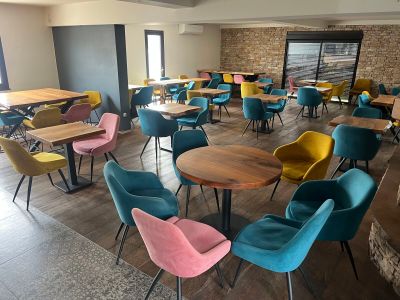 des chaises et des tables aux couleurs vives dans un restaurant, avec un mur de briques en arrière-plan
