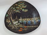 a black plate with a painting of boats on it