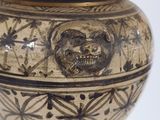 a vase with a lion head on it sitting on a table
