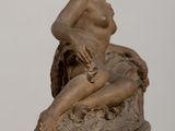 bronze statue of a woman sitting on a rock on a table