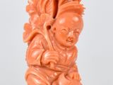 une figurine sculptée de couleur orange posée sur une surface blanche