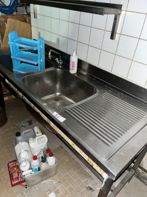 un évier au milieu d'une cuisine dont le plan de travail est encombré