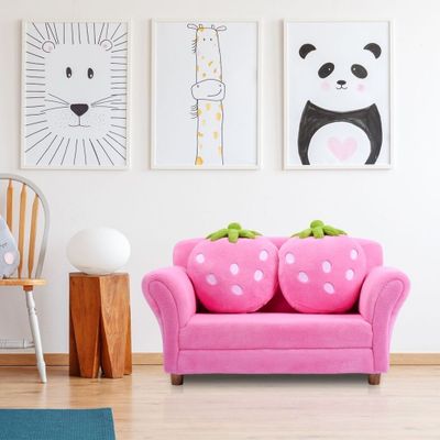 a pink couch in the corner of a room with pictures on the wall