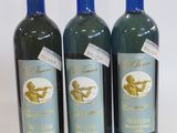 three bottles of wine are lined up on a white surface
