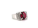 a close up of a ring with a red stone surrounded by diamonds