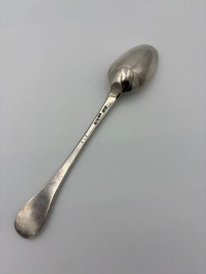 an old silver spoon with a spoon handle on a white surface