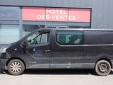 une camionnette garée devant un immeuble sur lequel est accrochée une enseigne indiquant « Hôtel des Ventes »