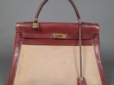 a red and beige bag with a handle on a gray surface