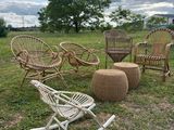 several wicker chairs and a rocking chair in a grassy field