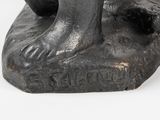statue of a dog with a ball in its mouth sitting on a rock