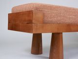 a wooden bench with two legs and a cushion on it