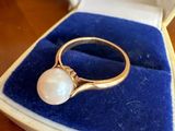 une photo d'une bague en perle dans un écrin posé sur une table