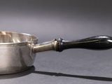 a silver saucepan with a wooden handle on a table
