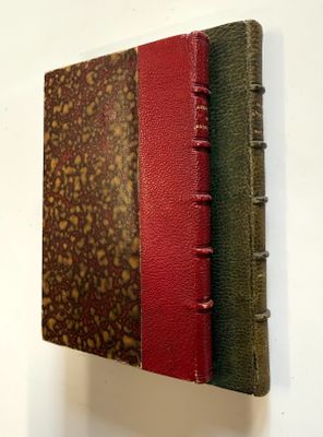 un vieux livre à la couverture rouge et verte posé sur un mur blanc