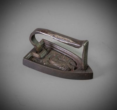 a small metal iron with a handle on a table