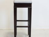 a stool with a white cushion on it in front of a white wall