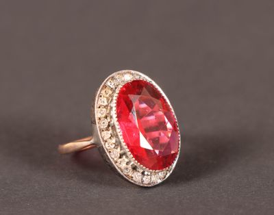 gros plan d'une bague avec une pierre rouge entourée de diamants