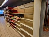 de nombreuses étagères vides dans un magasin, sur lesquelles sont disposées des bouteilles de vin
