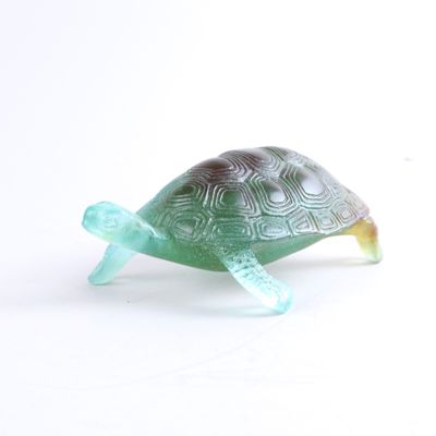 une figurine de tortue en verre posée sur une surface blanche