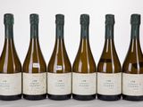 six bottles of wine are lined up in a row on a white surface