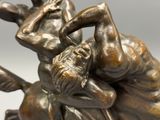 a bronze statue of two men wrestling each other