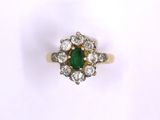 a close up of a green and white diamond ring on a white surface