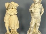 deux statues représentant un garçon et une fille debout l'un à côté de l'autre