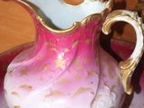 a pink and gold pitcher sitting on top of a plate