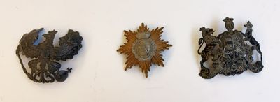 trois plaques métalliques sur un mur blanc, représentant un soleil et un aigle