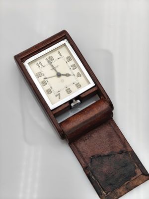 une image représentant une petite horloge posée sur une surface blanche