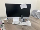 a desk with a computer, keyboard, phone, and water bottle on it