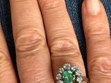 an image of a woman ' s hand with a diamond and emerald ring on it