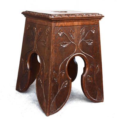 a small wooden stool with a carved design on it