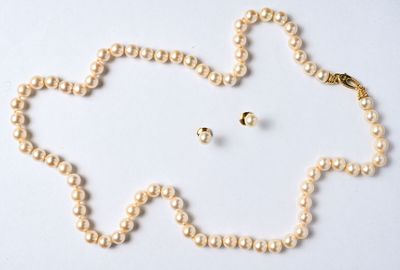 un collier de perles et une paire de boucles d'oreilles posés sur un fond blanc