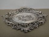 une assiette en argent finement décorée, sur laquelle figure l'image d'un cheval et de son cavalier