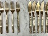 six forks and six knives are lined up on a marble surface