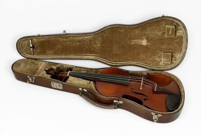 un vieil étui à violon contenant un violon, sur fond blanc