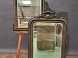 une paire de miroirs anciens posés sur un chevalet en bois devant un mur gris