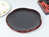 a black plate with a red design on it next to a box of matches and a plate with a red design on it