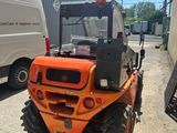 a small orange tractor parked in front of a building