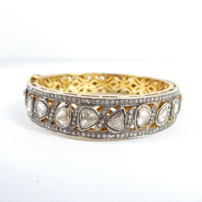 gros plan d'un bracelet en or et diamants sur fond blanc