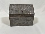 an old metal box with a floral design on the lid