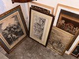de nombreux tableaux encadrés posés par terre à côté d'une horloge