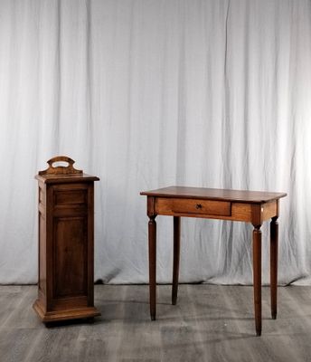 une petite table sur laquelle se trouve une horloge, à côté d'un petit meuble