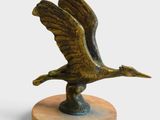 bronze sculpture of a bird on a wooden base on a white background