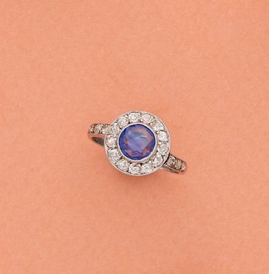 gros plan d'une bague avec une pierre bleue entourée de diamants