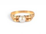 gros plan d'une bague en or contenant une perle