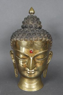 une tête de Bouddha en or surmontée d'une pierre rouge